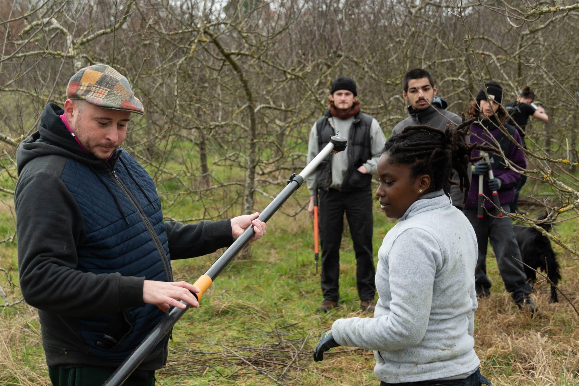 un formateur ÊTRE et Al'Terre Égaux explique au groupe de jeunes comment fonctionnent les outils pour tailler les arbres en formations multimétiers